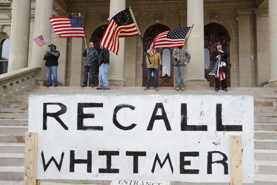 FILE - In this April 15, 2020, file photo protesters stand on the steps of the Michigan State Capitol in Lansing, Mich. Flag-waving, honking protesters drove past the Michigan Capito to show their displeasure with Gov. Gretchen Whitmer's orders to keep people at home and businesses locked during the new coronavirus COVID-19 outbreak. (AP Photo/Paul Sancya, File)