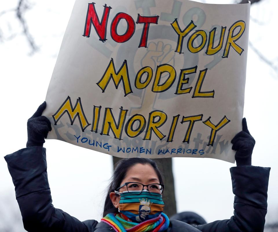 A woman wearing a Justice Ruth Bader Ginsburg face mask holds a sign during a vigil and rally against Asian hate crimes, Friday, March 26, 2021, at Chicago's Horner Park. The event is organized by local Chicago organizations led by Asian Americans and Pacific Islanders. (AP Photo/Shafkat Anowar) ORG XMIT: ILSA105