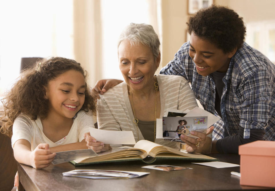 Grandmother and grandchildren looking at photographs (Jose Luis Pelaez / Getty Images)