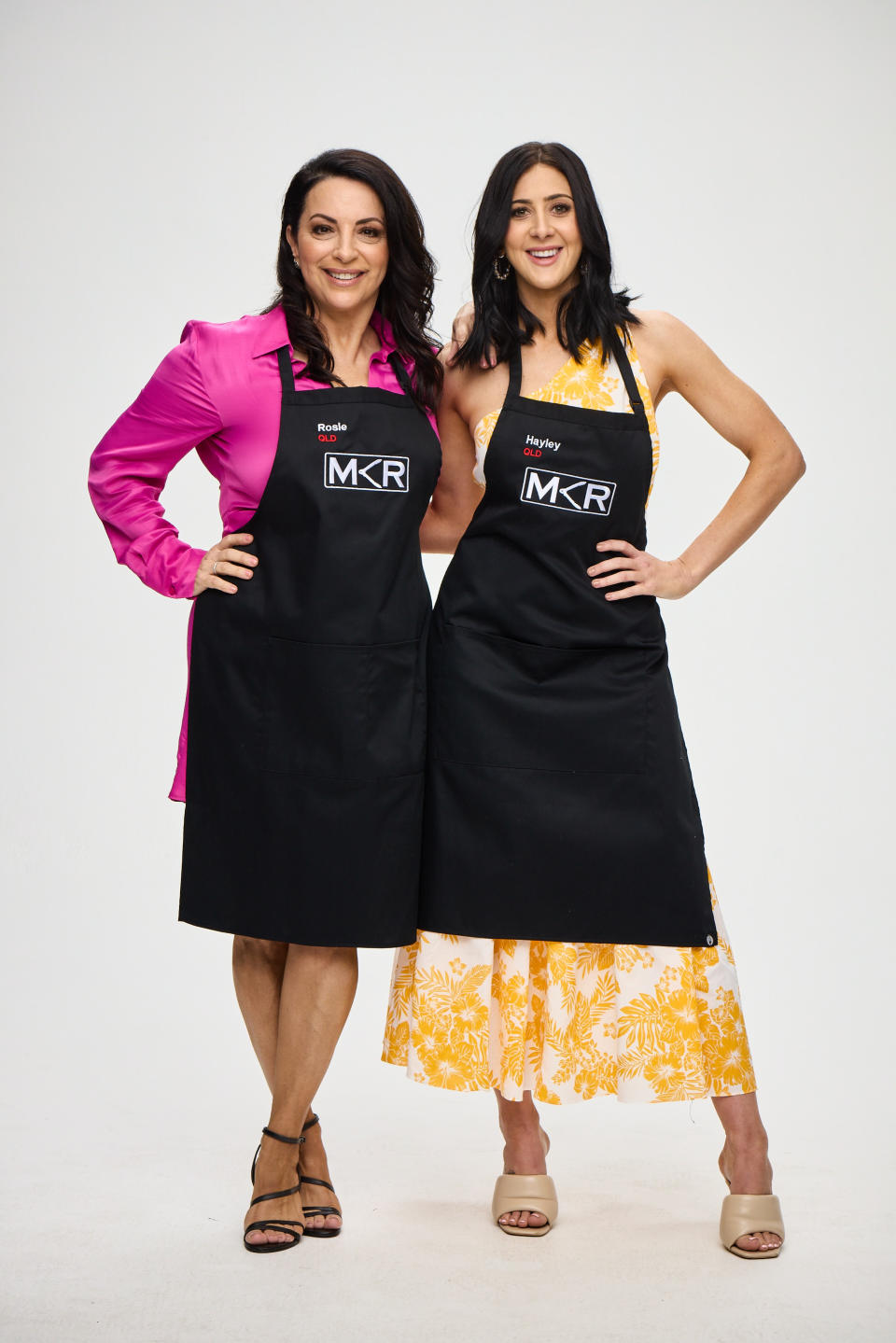 MKR 2022 contestants Rosie and Hayley from Queensland stand smiling in MKR aprons