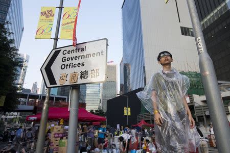 A student stands next to a sign, which originally read "Central Government Offices" and was modified to "Citizens' Headquarters", as riot police stand guard during a rally outside the government headquarters in Hong Kong September 28, 2014. REUTERS/Tyrone Siu