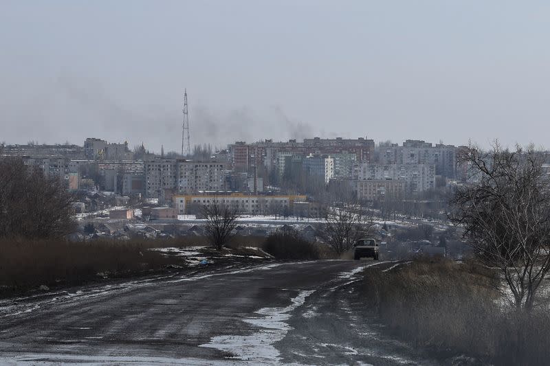 Smoke rises after a shelling as a car moves along a road in the frontline city of Bakhmut