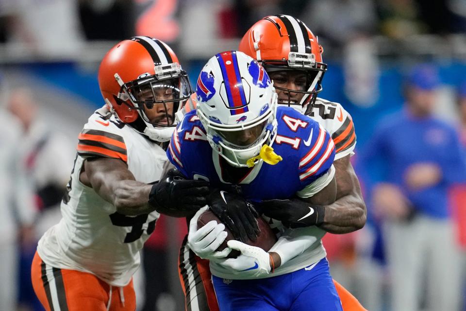 Buffalo Bills wide receiver Stefon Diggs (14) is tackled by Cleveland Browns cornerback Denzel Ward (21) and safety John Johnson III (43) during the second half of an NFL football game, Sunday, Nov. 20, 2022, in Detroit. (AP Photo/Paul Sancya)