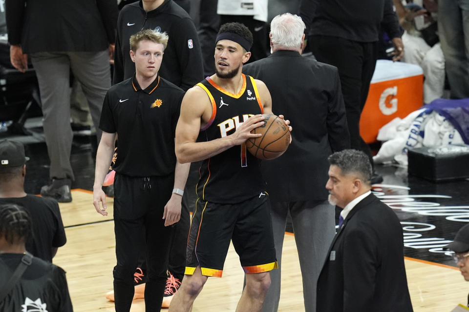 Phoenix Suns guard Devin Booker walks off the court with the basketball after Game 4 of an NBA basketball first-round playoff series loss against the Minnesota Timberwolves, Sunday, April 28, 2024, in Phoenix. The Timberwolves won 122-116, taking the series 4-0. (AP Photo/Ross D. Franklin)