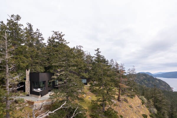 The wood-and-stone home blends into its forested landscape, presenting a peaceful oasis.