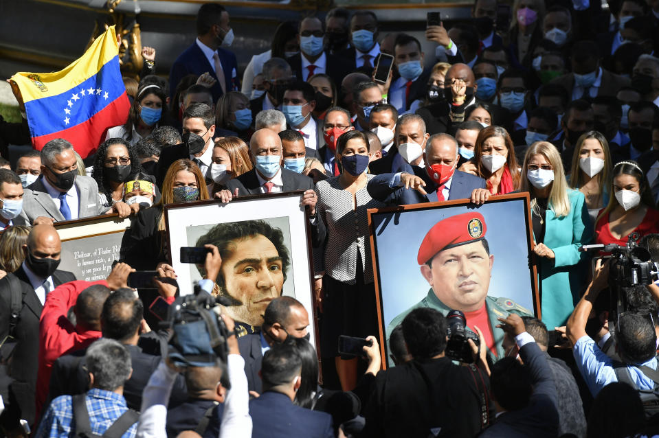 Los parlamentarios entrantes, algunos de los cuales fueron reelegidos, llevan imágenes del fallecido presidente venezolano Hugo Chávez, a la derecha, y delhéroe de la independencia Simón Bolívar, desde la cámara de la Asamblea Constitucional a la cámara de la Asamblea Nacional, mientras el partido socialista gobernante se prepara para asumir la presidencia del Congreso en Caracas, Venezuela, el martes 5 de enero de 2021. (AP Foto/Matias Delacroix)