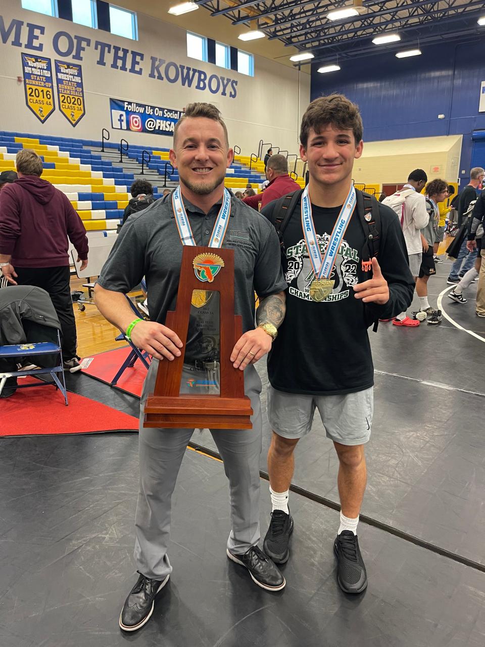 Palmetto Ridge head wrestling coach Blaine Ison and senior wrestler Brennan Van Hoecke pose with the 3A Dual State Championship trophy.
