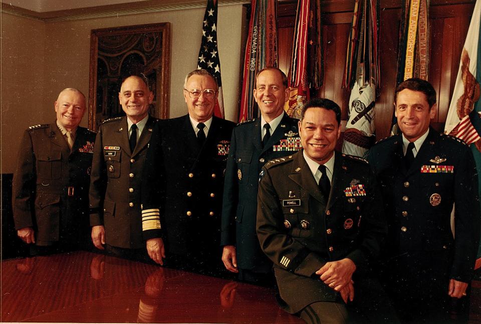 A group of men stand around the table while wearing military uniform