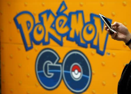 A man uses a mobile phone in front of an advertisement board bearing the image of Pokemon Go at an electronic shop in Tokyo, Japan, July 27, 2016. REUTERS/Kim Kyung-Hoon/File Photo