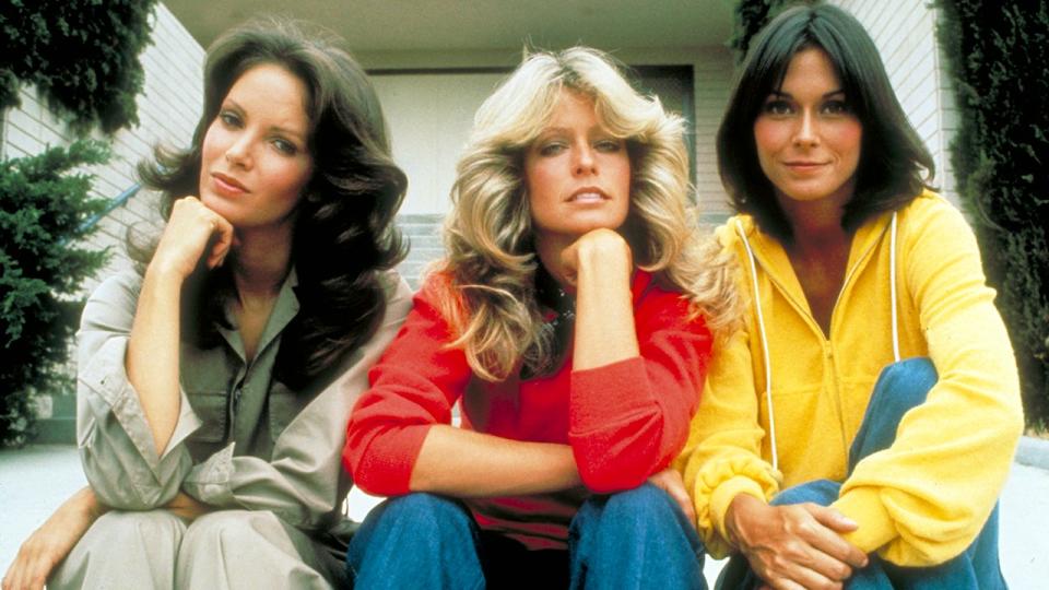 The cast of Charlie's Angels sitting down and looking directly at the camera