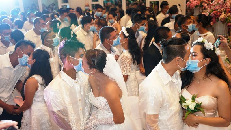 Filipino couples kiss while wearing their face masks in a government-sponsored mass wedding in Bacolod City