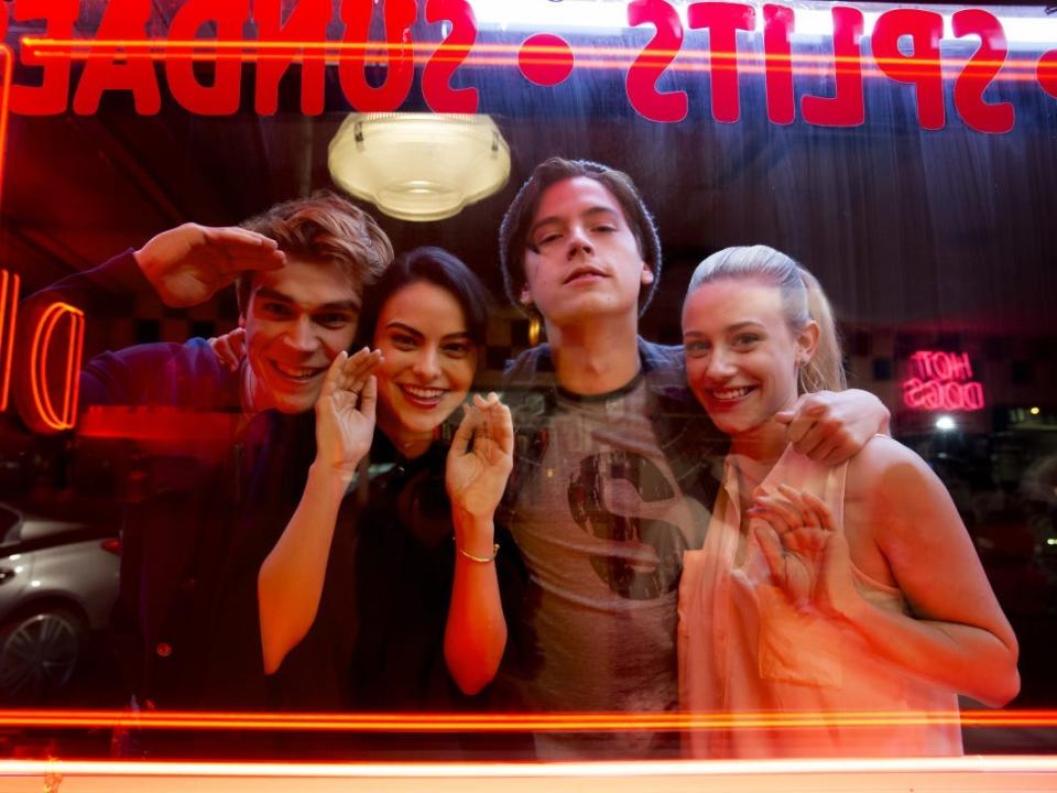 KJ Apa, Camila Mendes, Cole Sprouse, and Lili Reinhart looking through a window behind the scenes of season one of "Riverdale."