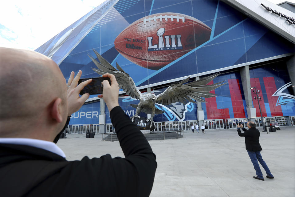 Jay Reid, left, takes a photo of Mercedes-Benz Stadium the evening before NFL football's Super Bowl, Saturday, Feb. 2, 2019, in Atlanta. (Curtis Compton/Atlanta Journal-Constitution via AP)