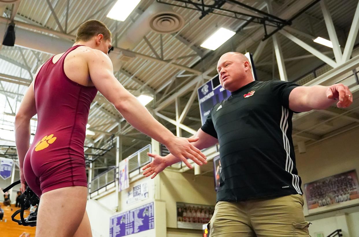 Bloomington North’s Cael Hickok (top) celebrates with head coach Roy Bruce after winning the 157-pound final during the IHSAA wrestling regional at Bloomington South on Saturday, Feb. 3, 2024.