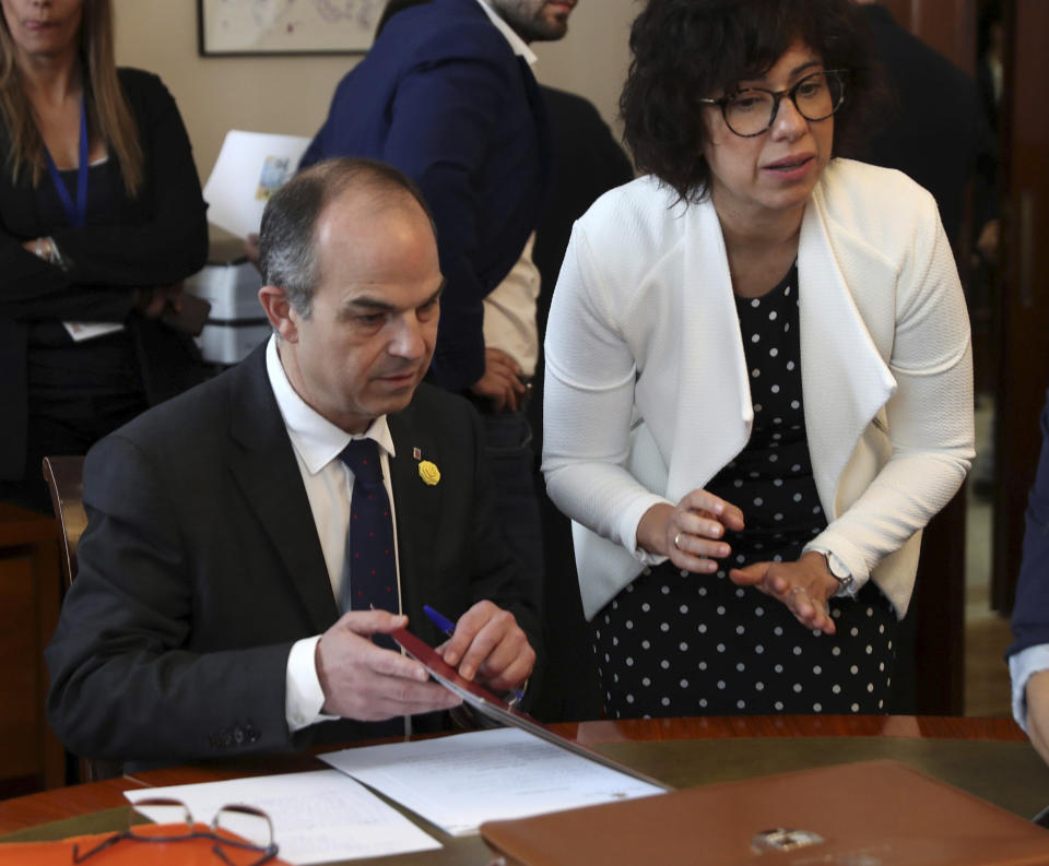 Catalan Councillor Jordi Turull, left, signs documents inside the Spanish parliament in Madrid, Spain, Monday May 20, 2019. The five separatist leaders on trial for Catalonia's 2017 secession attempt who were elected to the Spanish Parliament in April 28 elections have been escorted by police to pick up their official parliament credentials. The Supreme Court is allowing the five politicians to get their credentials on Monday and attend the opening session of the new Parliament on Tuesday.(J.J. Guillen/Pool Photo via AP)