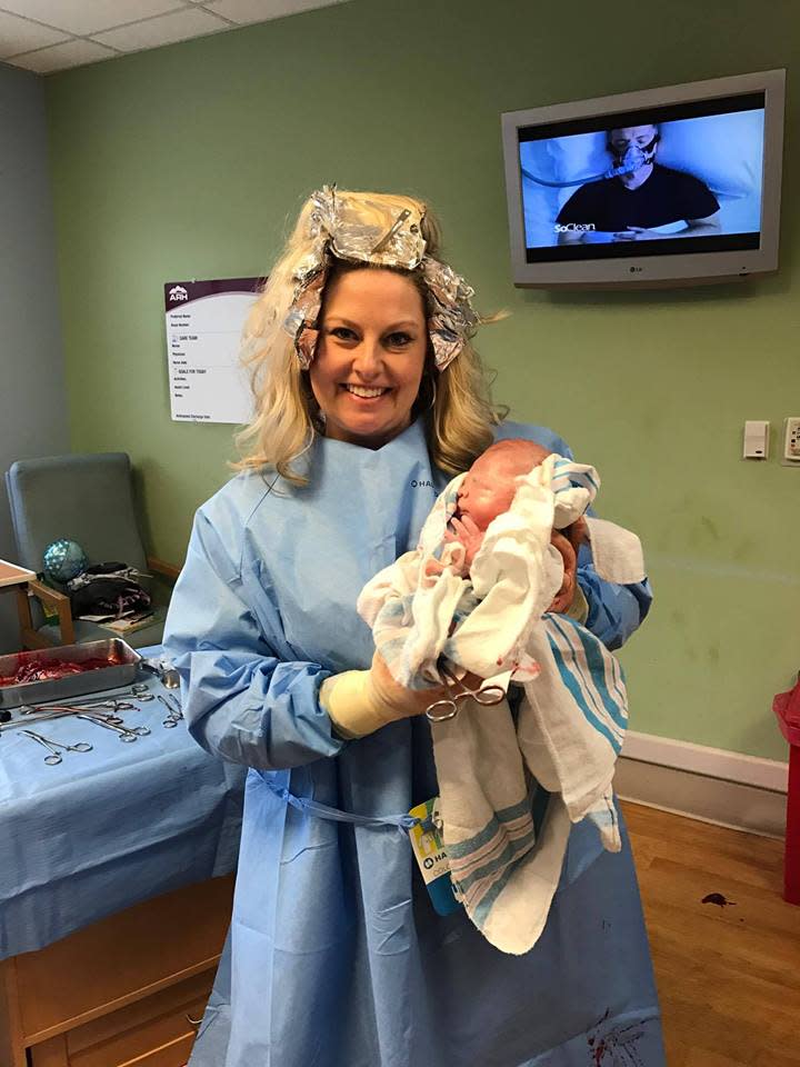 Nurse with hair foils holding newborn