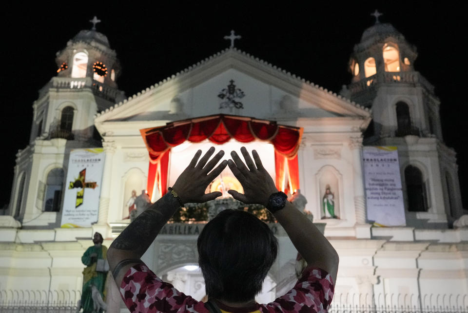 A devotee prays in front of the Quiapo church as he waits for the "Walk of Faith" procession as part of celebrations for the feast day of the Black Nazarene, a centuries-old charred statue of Jesus Christ, on Sunday, Jan. 8, 2023, in Manila, Philippines. The annual Black Nazarene feast day which will be held on Jan. 9 draws massive numbers of devotees who pray for the sick and a better life in this predominantly Roman Catholic nation. (AP Photo/Aaron Favila)