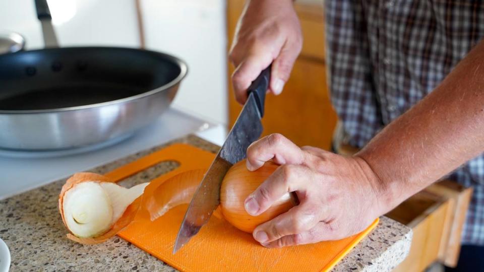 Luke, an Arroyo Grande resident who recently moved into a permanent home using a housing choice voucher, cuts onions for a meal in his new home.