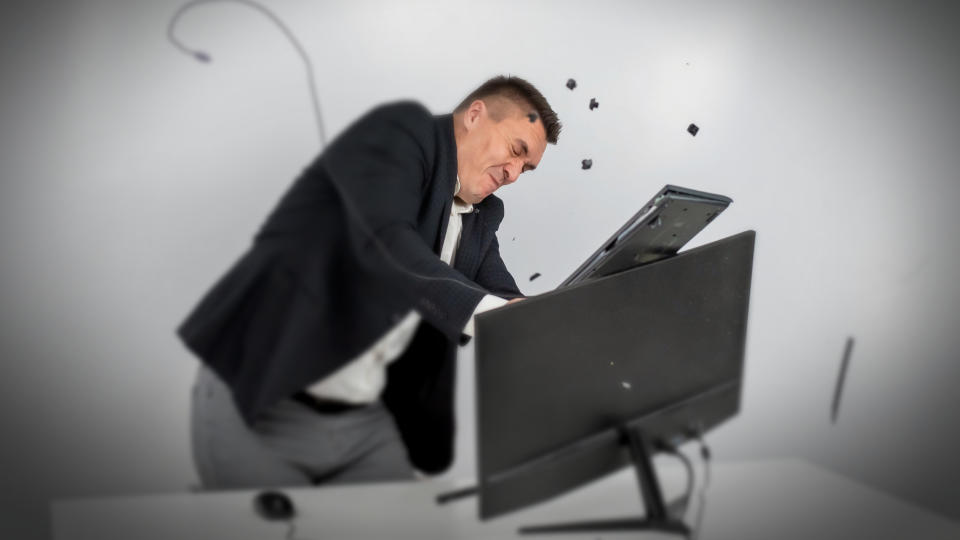 Person in a suit gets angry and smashes the keyboard on the monitor