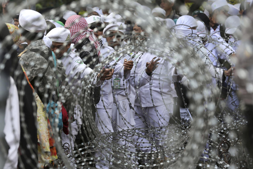 <p>Muslim protesters are seen through razor wire barricades during a rally against the persecution of Rohingya Muslims outside the Myanmar’s Embassy in Jakarta, Indonesia, Wednesday, Sept. 6, 2017. (Photo: Tatan Syuflana/AP) </p>