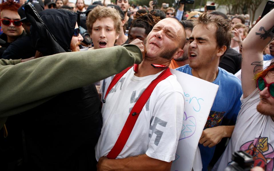 A man wearing a shirt with swastikas on it is punched by an unidentified member of the crowd near the site of a planned speech by white nationalist Richard Spencer, who popularized the term 'alt-right', at the University of Florida campus on October 19, 2017 in Gainesville - Getty Images North America