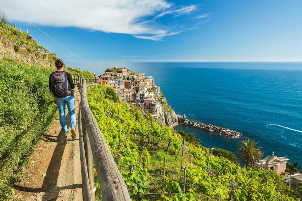 Woman hiking on the blue path in vineyard near Manarola village, Cinque Terre, Italy