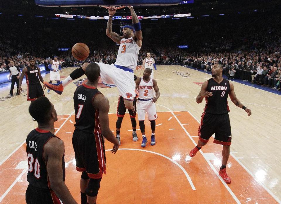 New York Knicks' Kenyon Martin (3) holds onto the rim after dunking the ball in front of Miami Heat's Chris Bosh (1) and Norris Cole (30) during the first half of an NBA basketball game on Thursday, Jan. 9, 2014, in New York. (AP Photo/Frank Franklin II)