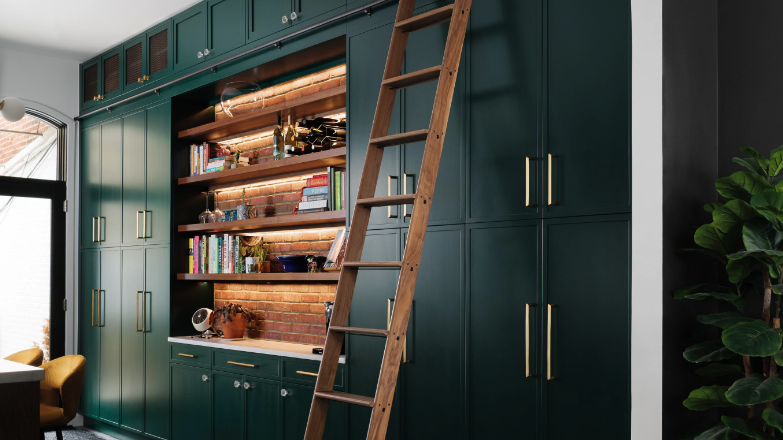 a ladder leaning against dark green kitchen cabinets