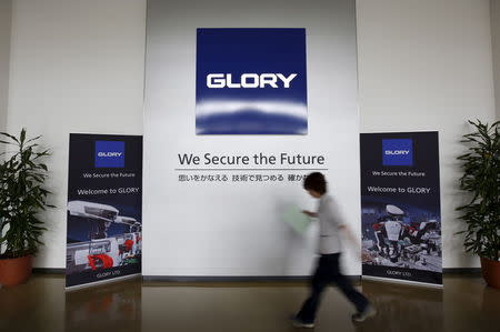 An employee walks past at the entrance of a factory of Glory Ltd., a manufacturer of automatic change dispensers, in Kazo, north of Tokyo, Japan, July 1, 2015. REUTERS/Issei Kato