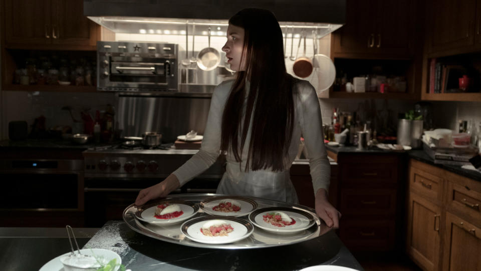 A woman holds plates of food in Servant