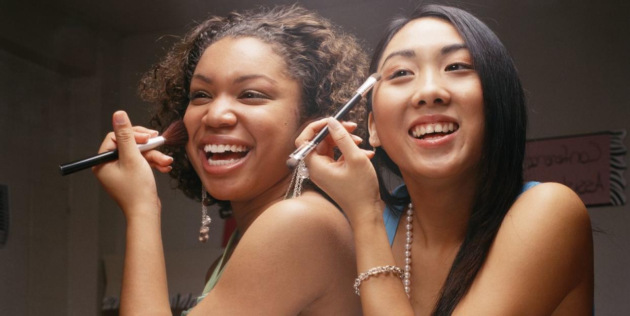 teenage girls 18 20 applying make up in bathroom