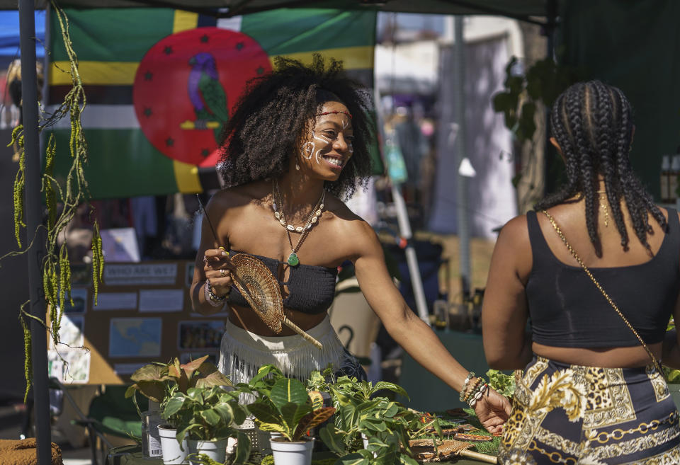 Reanna Barry, left, from Dominica, the island country in the Caribbean, sells natural products and plants during a Juneteenth commemoration at Leimert Park in Los Angeles on Saturday, June 18, 2022. (AP Photo/Damian Dovarganes)