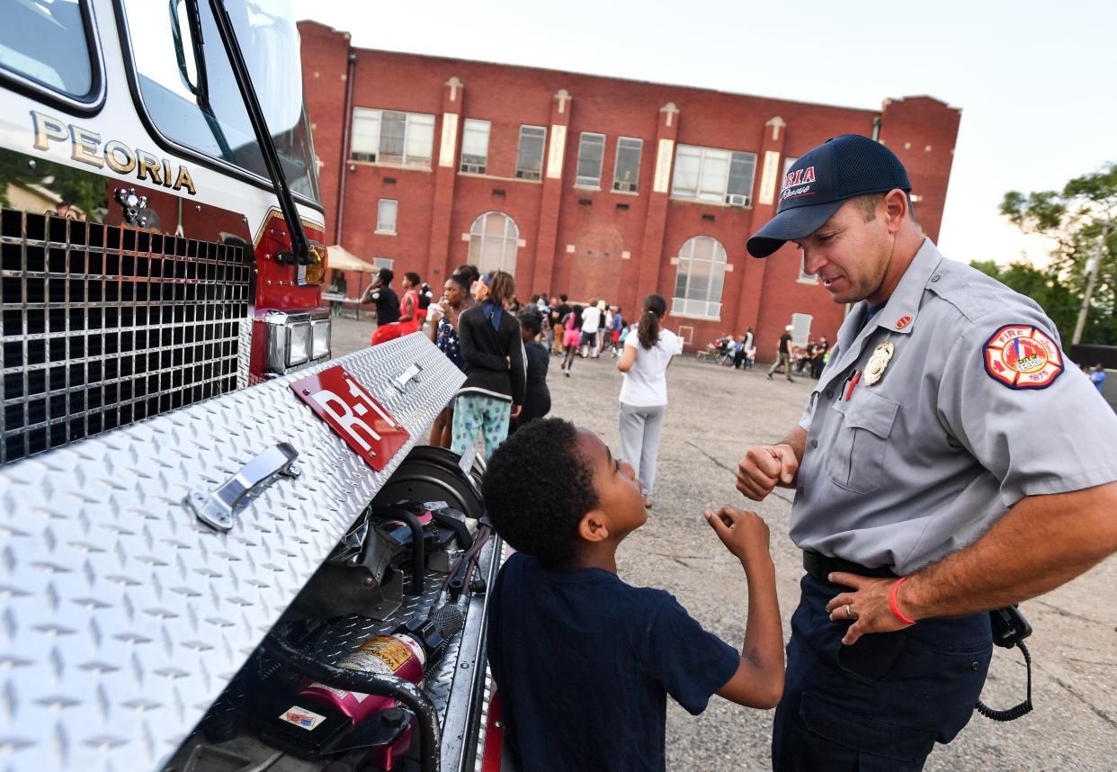 In this 2017 file photo, Peoria Fire Department Capt. Shawn Sollberger greets children around a fire truck at the National Night Out at East Bluff Community Center. (RON JOHNSON/JOURNAL STAR)