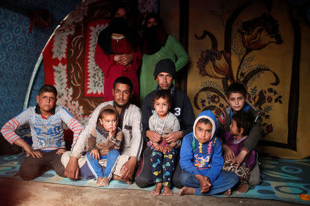Displaced Iraqi Lafi and his family pose for a photograph in a tent at Hammam al-Alil camp south of Mosul, Iraq, March 29, 2017. Thirteen people live in the tent. In Mosul, they all lived under the same roof. In the camp, the adults spend a lot of time looking for food and water, Lafi said. REUTERS/Suhaib Salem
