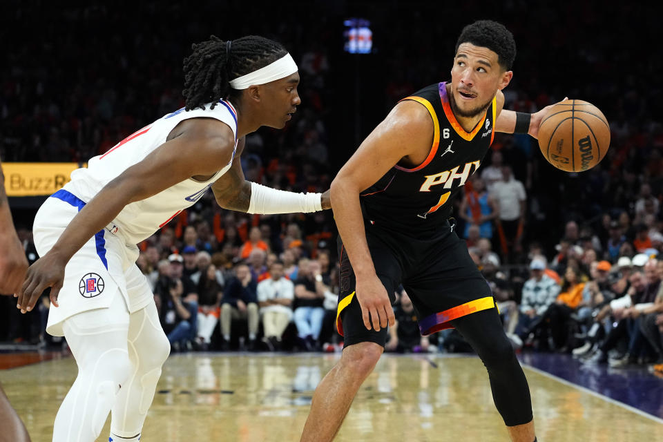 Phoenix Suns guard Devin Booker, right, looks to pass as Los Angeles Clippers guard Terance Mann defends during the second half of Game 5 of a first-round NBA basketball playoff series, Tuesday, April 25, 2023, in Phoenix. (AP Photo/Matt York)