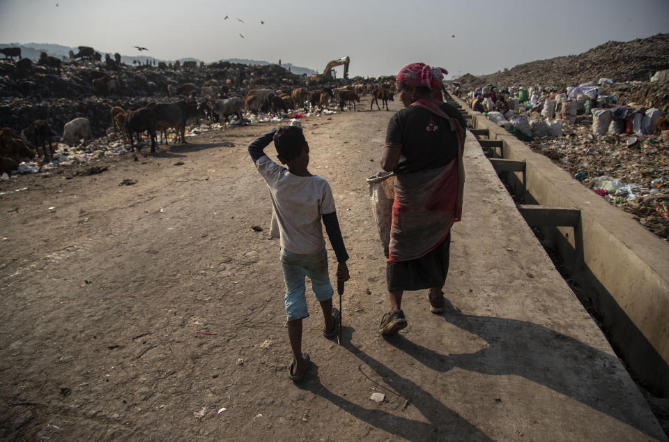 Imradul Ali, 10, left, and his mother Anuwara Beghum, 30, arrive to look for recyclable material at a landfill on the outskirts of Gauhati, India, Thursday, Feb. 4, 2021. Once school is done for the day, Ali, rushes home to change out of his uniform so that he can start his job as a scavenger in India’s remote northeast. Coming from a family of scavengers or “rag pickers," Ali started doing it over a year ago to help his family make more money. Ali says he doesn’t want to spend his life doing this, but he doesn’t know what the future holds. (AP Photo/Anupam Nath)