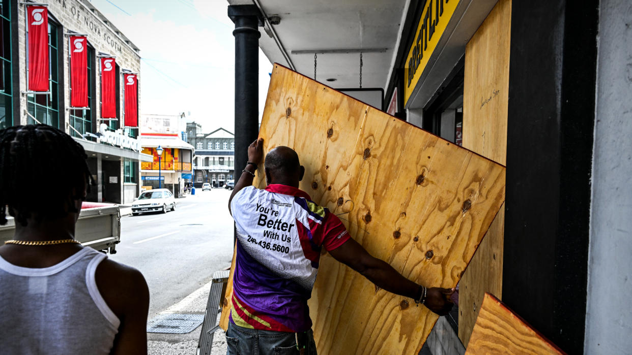  Man boards up shop window in Bridgetown, Barbados, before Hurricane Beryl. 