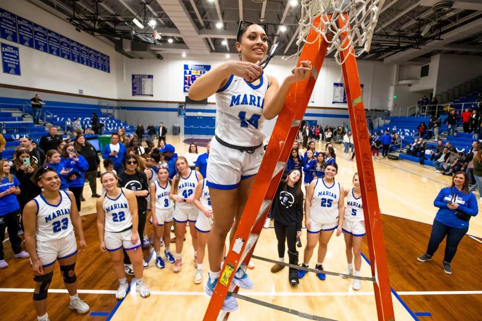Marian's Nevaeh Foster (14) cuts a piece of the net off after winning the Marian vs. Saint Joseph girls sectional championship basketball game Saturday, Feb. 4, 2023 at Marian High School.