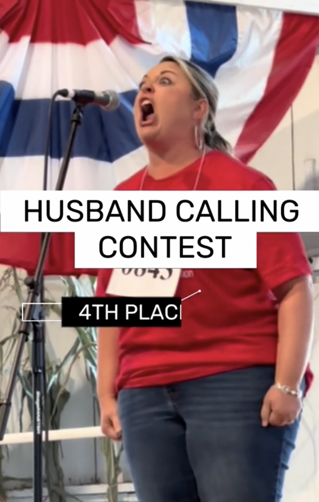 A woman standing at microphone and participating in the "Husband Calling Contest"
