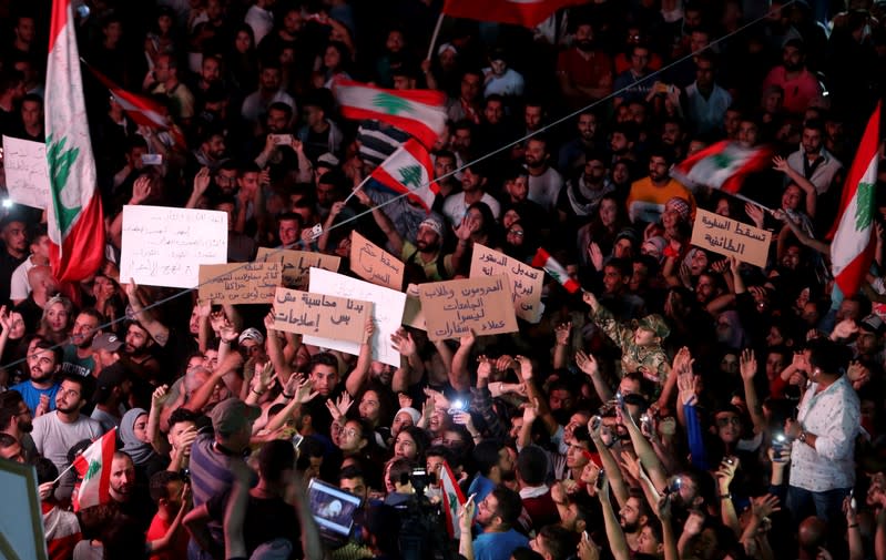 Demonstrators carry Lebanese flags during an anti-government protest in the southern city of Nabatiyeh