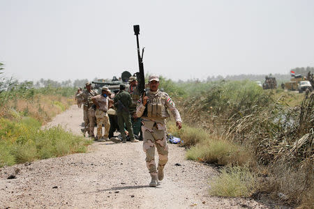 A member of Iraqi security forces walks with his weapon near Falluja, Iraq, May 25, 2016. REUTERS/Thaier Al-Sudani