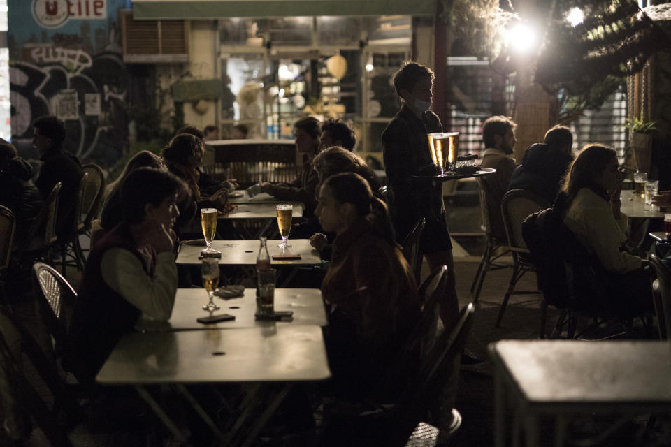 People enjoy drinks at a bar terrace in Marseille, southern France, Saturday, Oct. 17, 2020. France is deploying 12,000 police officers to enforce a new curfew that came into effect Friday night for the next month to slow the virus spread, and will spend another 1 billion euros to help businesses hit by the new restrictions. (AP Photo/Daniel Cole)