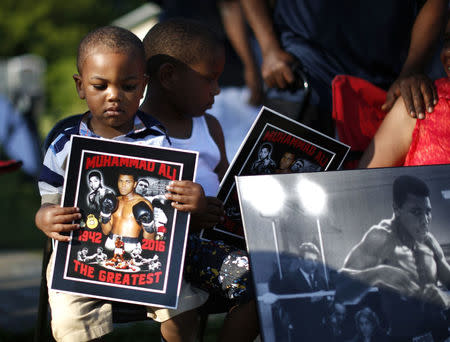 Brandon Liggons, 2, holds an image of Muhammad Ali during the funeral procession. REUTERS/Lucy Nicholson