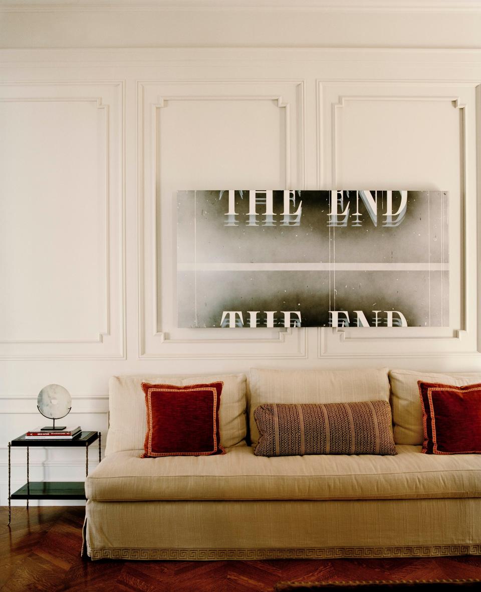 This painting by Ed Ruscha in the living room–screening room was commissioned by the owners and rises to reveal portholes that serve the adjacent projection booth. The sofa by Victoria Hagan is upholstered in Clarence House fabric.