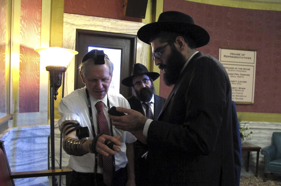 Rabbi Berry Nash, right, prays as Montana Rep. Dave Fern, R-Whitefish, wears boxes containing Torah versus called Tefillin on Wednesday, Jan. 18, 2017 in Helena, Mont. Nash was among a delegation of Orthodox Jewish rabbis from the U.S. and Canada who met with Fern and other state leaders to thank them for defending the Jewish community in Whitefish when it was threatened and harassed by white supremacists last month. (AP Photo/Matt Volz).