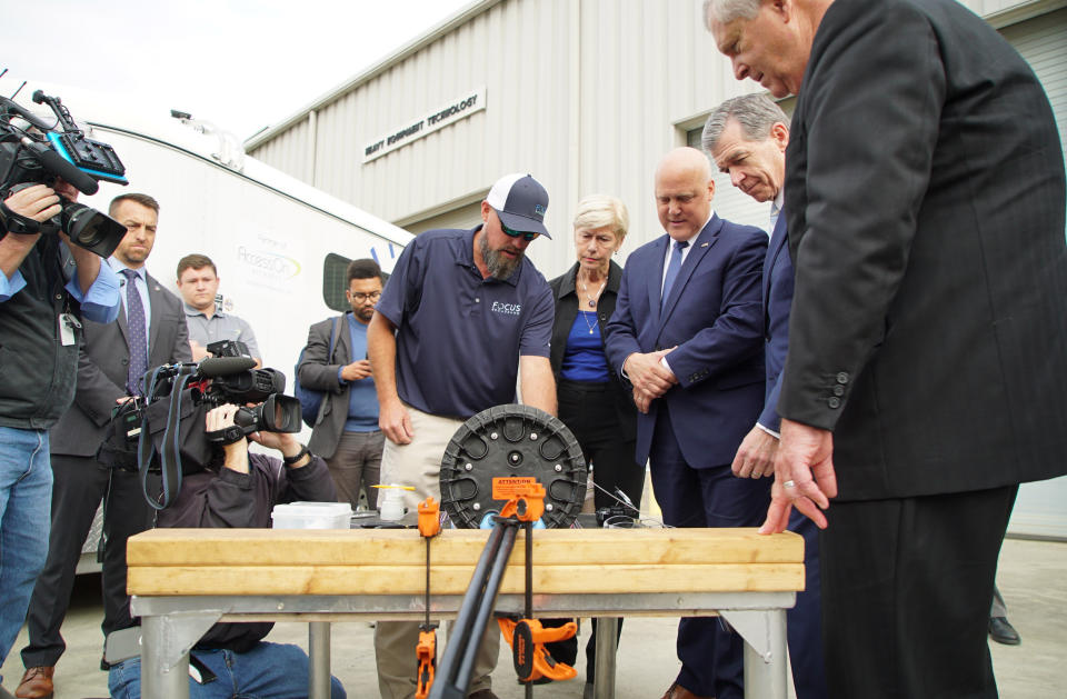 FILE - From far right to left, U.S. Agriculture Sec. Tom Vilsack, North Carolina Gov. Roy Cooper and White House adviser Mitch Landrieu look at broadband internet equipment during an event at Wake Tech Community College in Raleigh, N.C., on Thursday, Oct. 27, 2022. (AP Photo/Allen G. Breed, File)