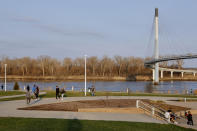 In this April 6, 2020 photo, residents stroll along the Missouri River in Omaha, Neb., as Council Bluffs, Iowa, is seen across the river. As most governors have imposed stay-at-home orders that public health officials say are essential to slowing the spread of the new coronavirus, leaders in a handful of states have steadfastly refused to take the action, arguing it's unneeded and potentially harmful. (AP Photo/Nati Harnik)