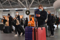 Varios viajeros esperan en la estación de trenes de King's Cross después de que entraran en vigor las nuevas restricciones en Londres. (Photo by Victoria Jones/PA Images via Getty Images)