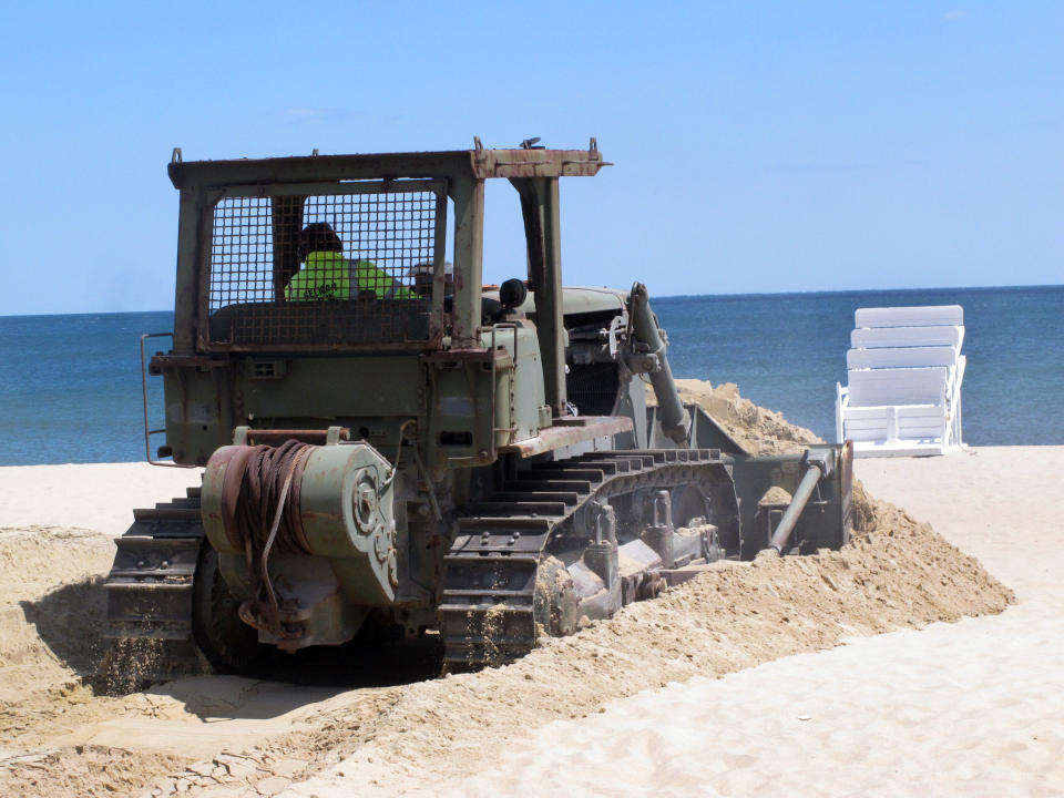 In this Tuesday, May 12, 2020 photo, workers prepare the beach in Belmar, N.J. for the summer season amid the coronavirus pandemic. Gov. Phil Murphy is expected to issue guidelines on Thursday, May 14, 2020, on when and how New Jersey's beaches can begin to reopen during the COVID-19 pandemic. (AP Photo/Wayne Parry)