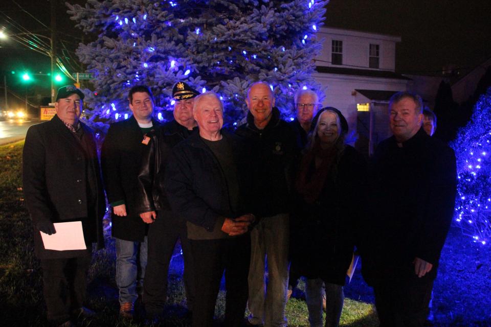 Feasterville Business Association held its 22nd annual Project Blue Light tree lighting ceremony outside the Lower Southampton Library Thursday. Pictured, from left, are township supervisor Steve Castle, Rep. Joe Hogan, Police Chief Ted Krimmel, retired township supervisor Ed Shannon, township supervisor Ray Weldie, event chairperson Michael J. Hughes, township supervisor Deborah Kaplan, and Rev. John J. Kelley of the Assumption BVM Catholic Church in Feasterville.